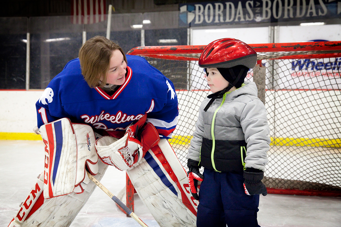 Hockey player helping child on ice